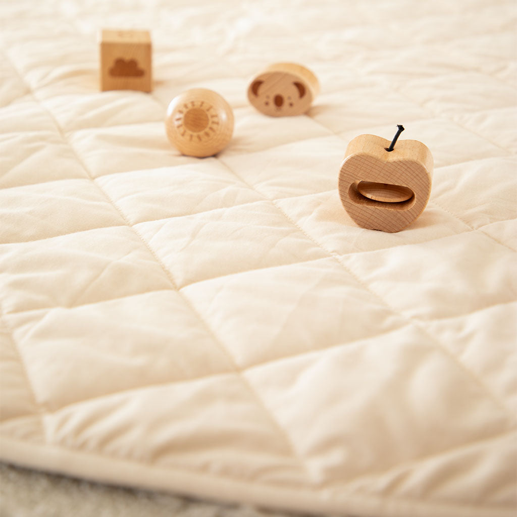 close up of organic cotton play mat padding thickness and wooden blocks